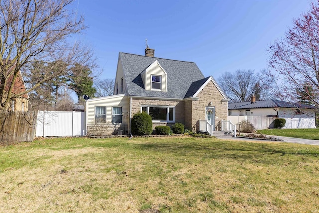 view of front of property featuring roof with shingles, fence, stone siding, a front yard, and a chimney