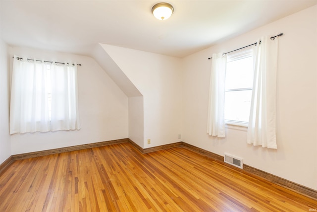 additional living space featuring baseboards, visible vents, vaulted ceiling, and light wood finished floors
