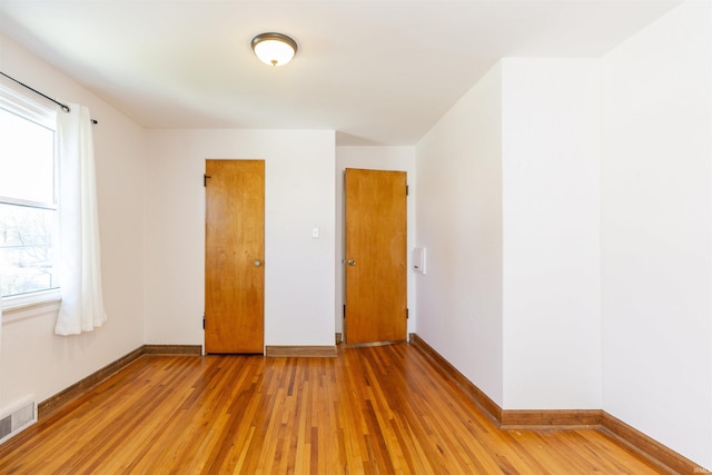 empty room with baseboards, light wood-type flooring, and visible vents
