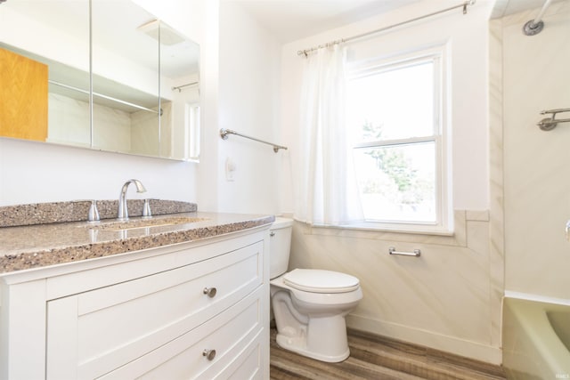 bathroom featuring toilet, vanity,  shower combination, wood finished floors, and baseboards