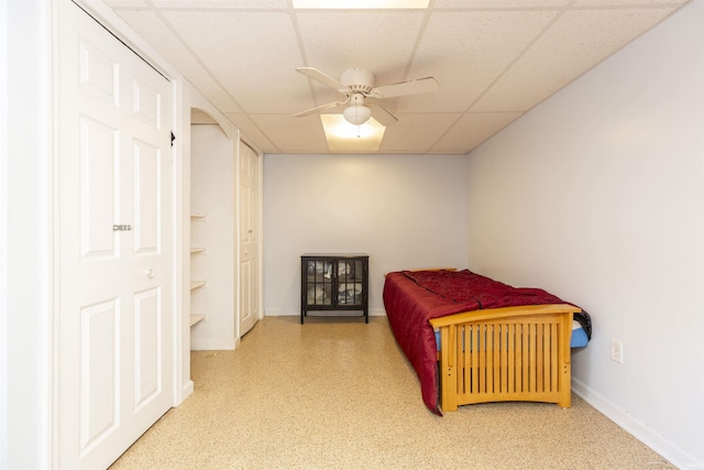 bedroom with a drop ceiling, baseboards, and ceiling fan