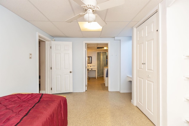 bedroom with baseboards, connected bathroom, a paneled ceiling, and ceiling fan