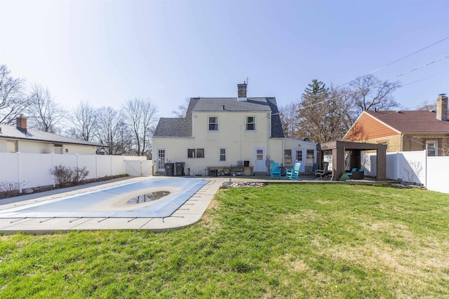 rear view of property with a patio, a fenced backyard, a jacuzzi, a yard, and a chimney