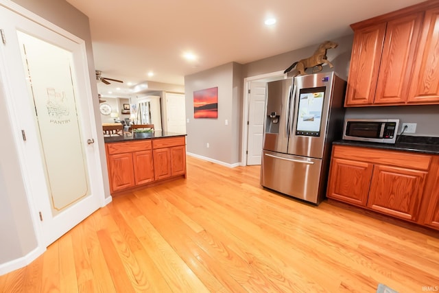 2860 E Moffett Ln, Bloomington, IN 47401 - kitchen with brown cabinets, stainless steel appliances, dark countertops, and light wood finished floors