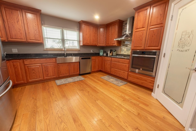 2860 E Moffett Ln, Bloomington, IN 47401 - kitchen featuring a sink, light wood finished floors, appliances with stainless steel finishes, brown cabinetry, and wall chimney range hood