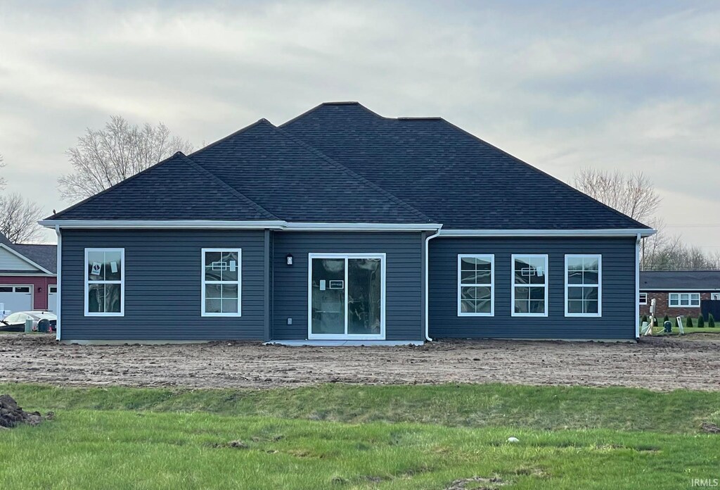 back of house with a shingled roof and a yard