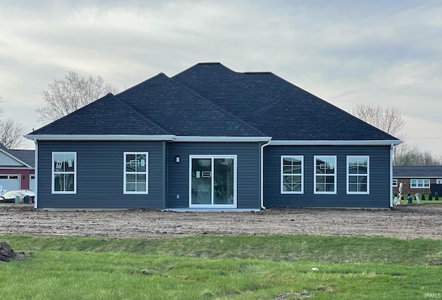 back of house with a shingled roof and a yard