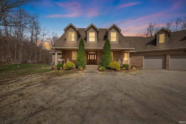 4277 S 100 W, Williamsport, IN 47993 - cape cod-style house with dirt driveway, a garage, brick siding, roof with shingles, and a porch