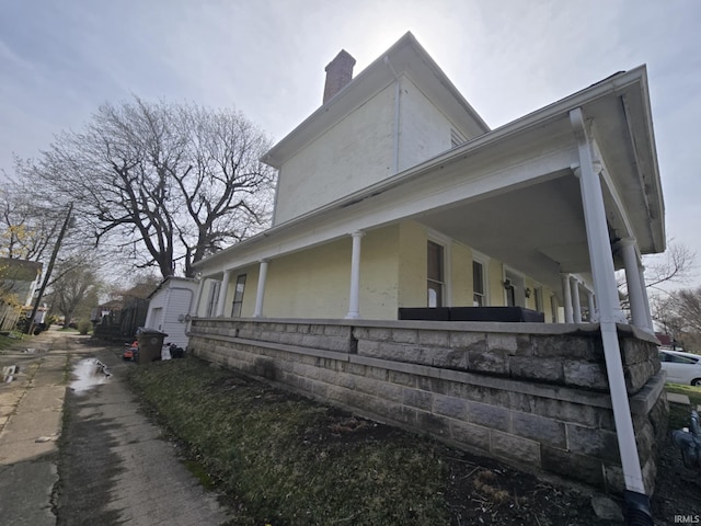 view of home's exterior featuring a chimney and covered porch