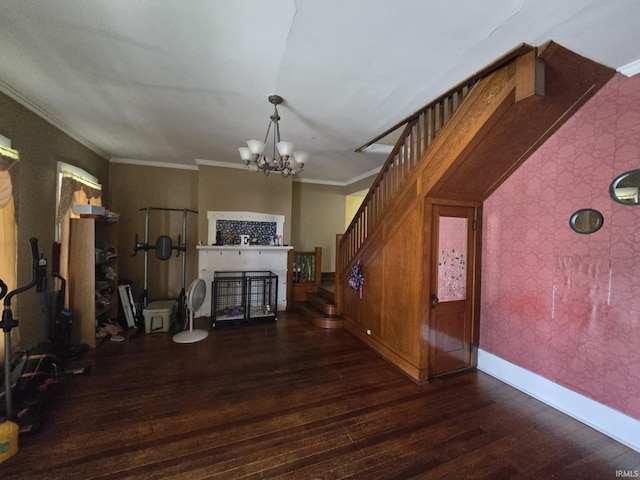 unfurnished living room with crown molding, baseboards, wood finished floors, wallpapered walls, and an inviting chandelier