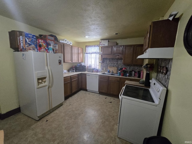 kitchen featuring a textured ceiling, light countertops, white appliances, light floors, and washer / dryer