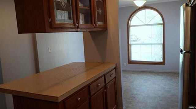 905 Stewart Ave, Evansville, IN 47715 - kitchen with healthy amount of natural light, light countertops, glass insert cabinets, brown cabinetry, and crown molding