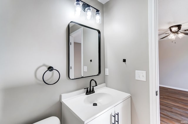 bathroom featuring toilet, vanity, a ceiling fan, wood finished floors, and baseboards
