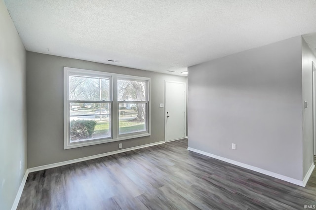 interior space featuring dark wood-type flooring, visible vents, a textured ceiling, and baseboards
