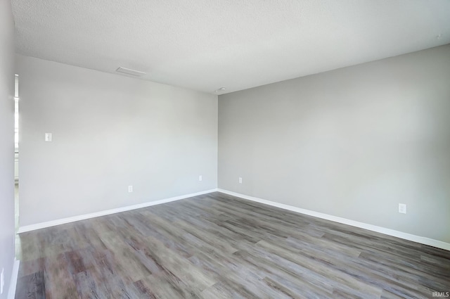 unfurnished room with baseboards, wood finished floors, and a textured ceiling