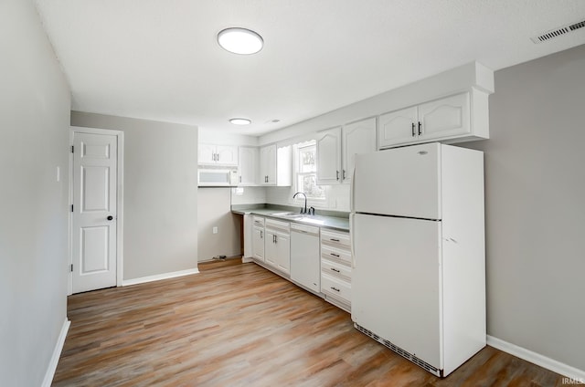 kitchen with white appliances, white cabinets, light wood-style flooring, and a sink