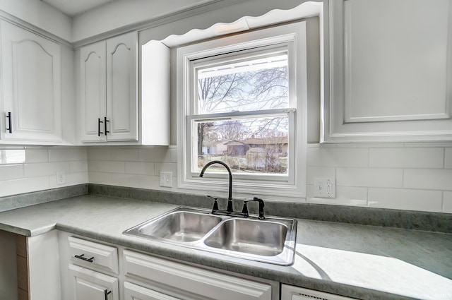 kitchen with white cabinets, decorative backsplash, and a sink