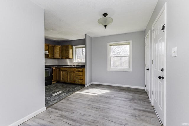 kitchen with baseboards, dark countertops, wood finished floors, and stove