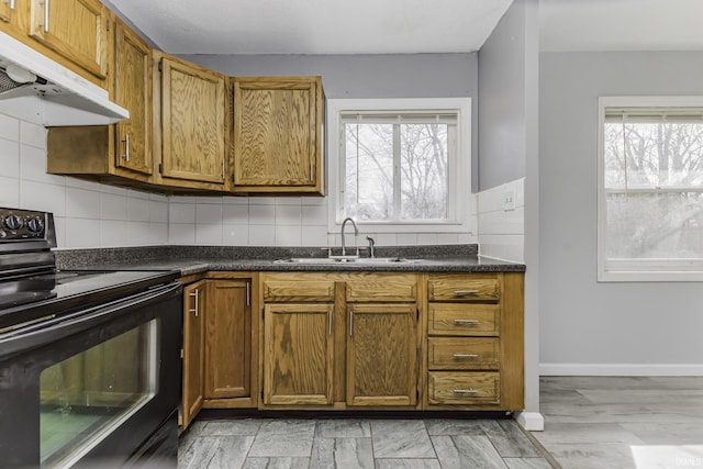 kitchen with under cabinet range hood, black electric range oven, a sink, and plenty of natural light