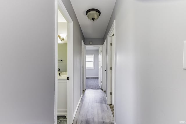 hall with baseboards and light wood finished floors