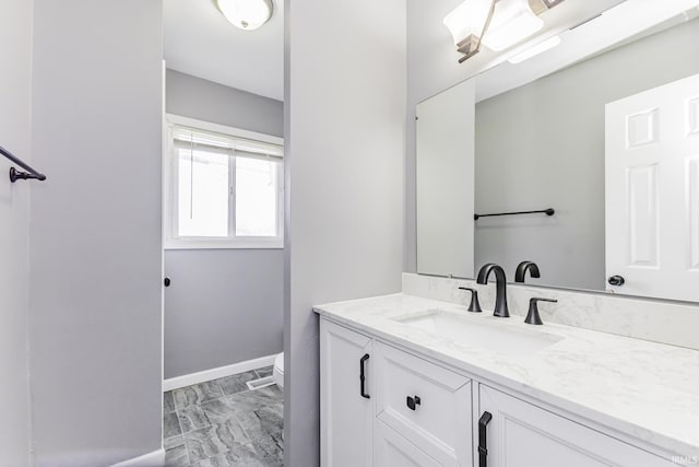 bathroom with baseboards, toilet, and vanity