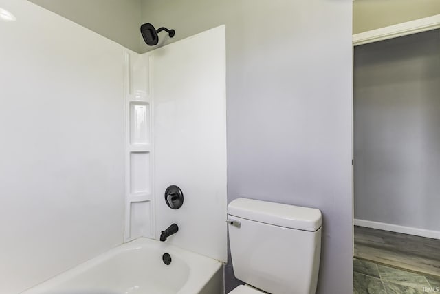 bathroom with bathtub / shower combination, toilet, and baseboards