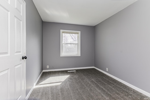 spare room with baseboards, dark colored carpet, and visible vents