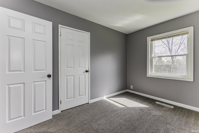unfurnished bedroom with baseboards, visible vents, and carpet