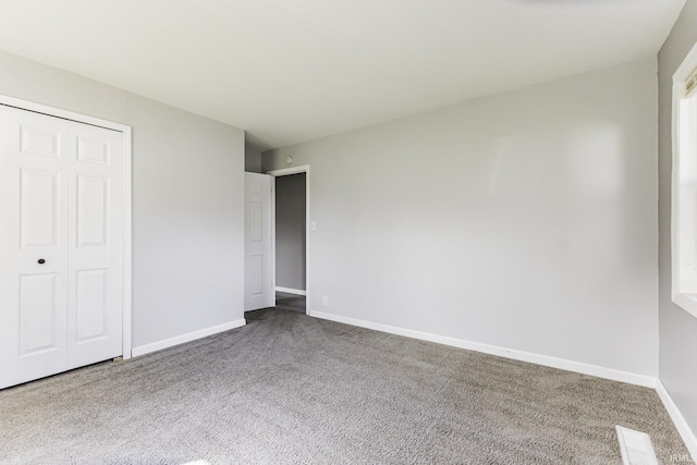 unfurnished bedroom featuring baseboards, carpet flooring, visible vents, and a closet