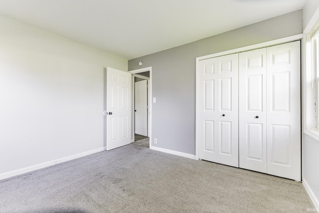 unfurnished bedroom featuring baseboards, a closet, and carpet