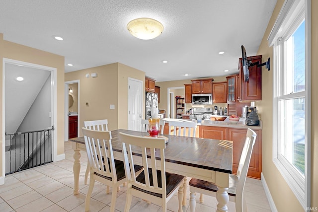 dining space with light tile patterned flooring, a textured ceiling, baseboards, and recessed lighting
