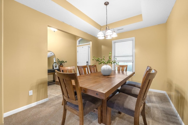 dining area with a raised ceiling, light carpet, baseboards, visible vents, and an inviting chandelier
