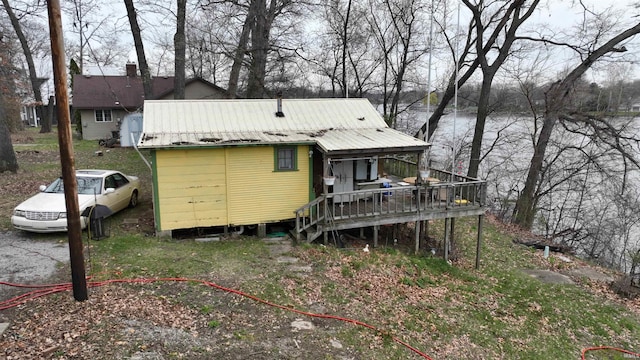 back of property with a deck with water view and metal roof