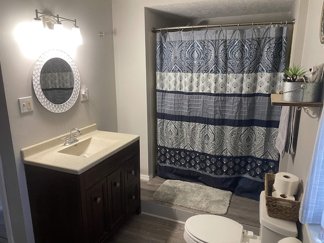 bathroom with toilet, curtained shower, vanity, wood finished floors, and a textured ceiling