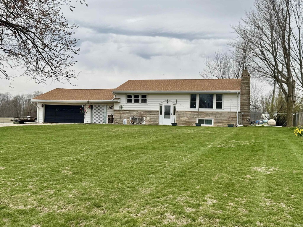 6510 E 500 S, Wabash, IN 46992 - view of front of property with an attached garage, a chimney, stone siding, and a front lawn