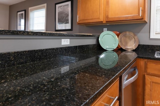 room details with brown cabinetry and dark stone counters