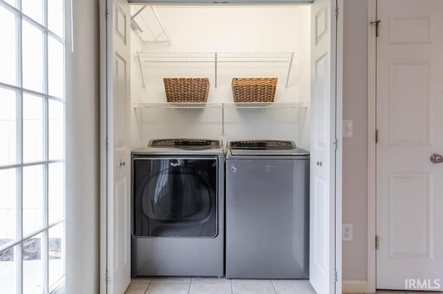 clothes washing area featuring laundry area, washing machine and clothes dryer, and light tile patterned floors