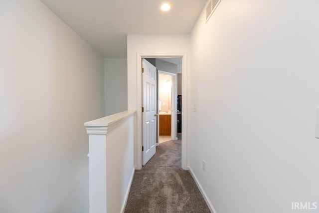 corridor with baseboards, an upstairs landing, dark colored carpet, and visible vents