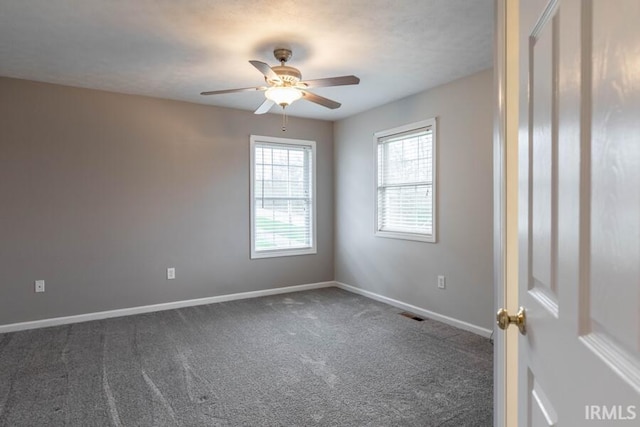empty room with visible vents, baseboards, dark colored carpet, and ceiling fan