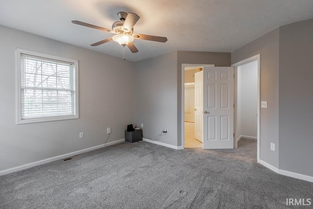 unfurnished bedroom with baseboards, a ceiling fan, connected bathroom, and carpet