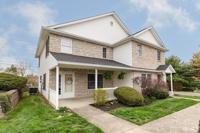 view of front of home with central AC unit, stone siding, a front lawn, and covered porch