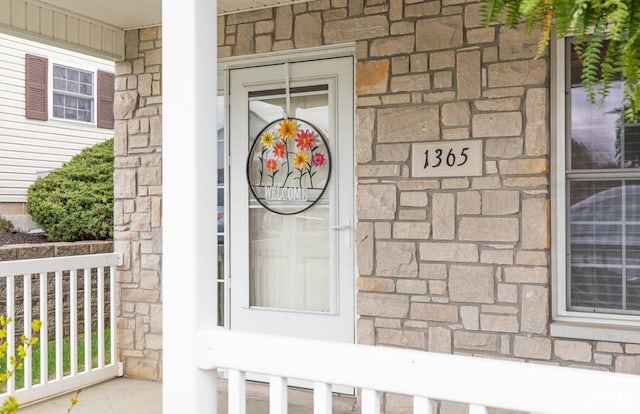 entrance to property with a porch and stone siding