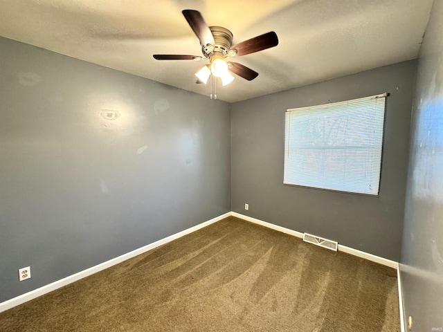 unfurnished room featuring a textured ceiling, a ceiling fan, visible vents, dark colored carpet, and baseboards