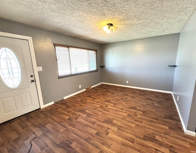 foyer with a textured ceiling, wood finished floors, baseboards, and visible vents