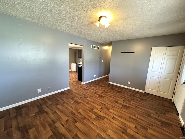 spare room with visible vents, baseboards, a textured ceiling, and dark wood-style floors