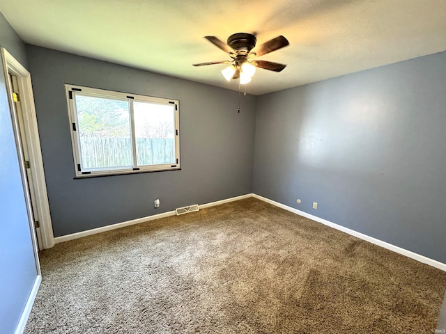 empty room featuring carpet floors, baseboards, a ceiling fan, and visible vents