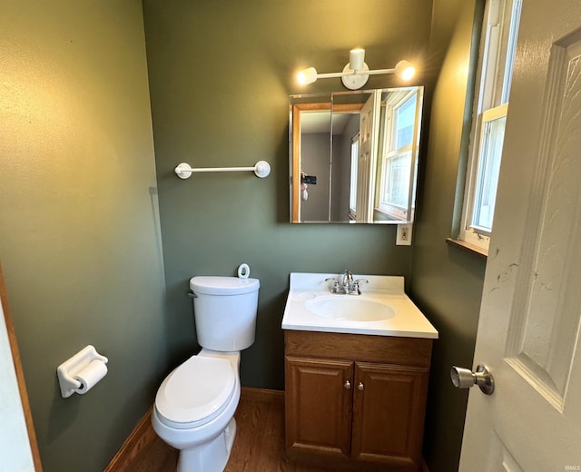bathroom with toilet, wood finished floors, vanity, and baseboards