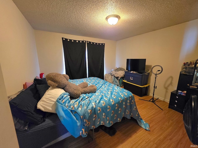 bedroom featuring wood finished floors and a textured ceiling