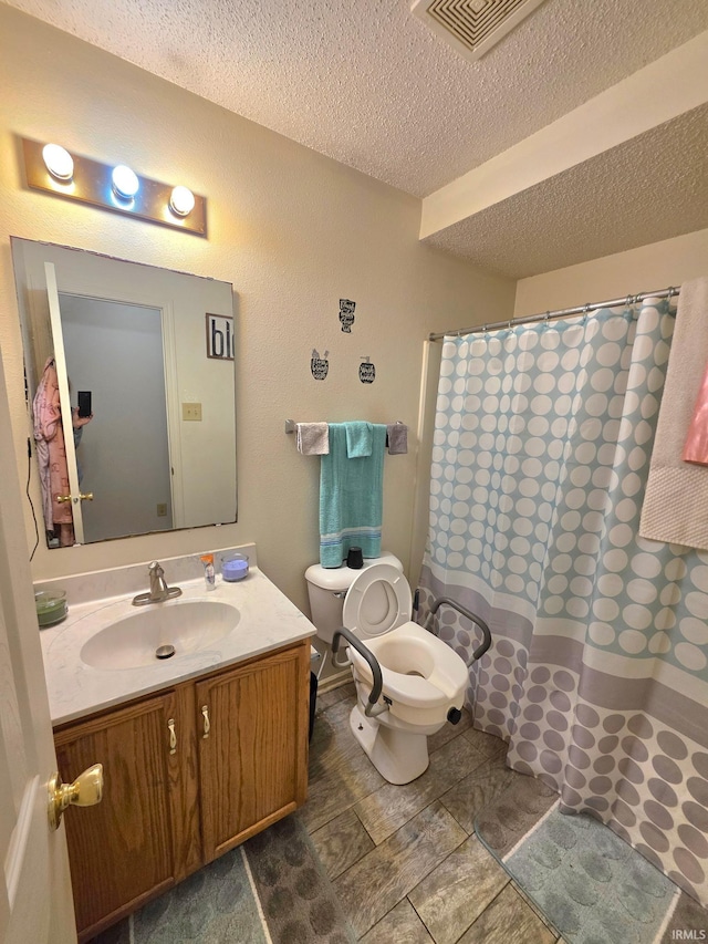full bath featuring vanity, curtained shower, toilet, visible vents, and a textured ceiling