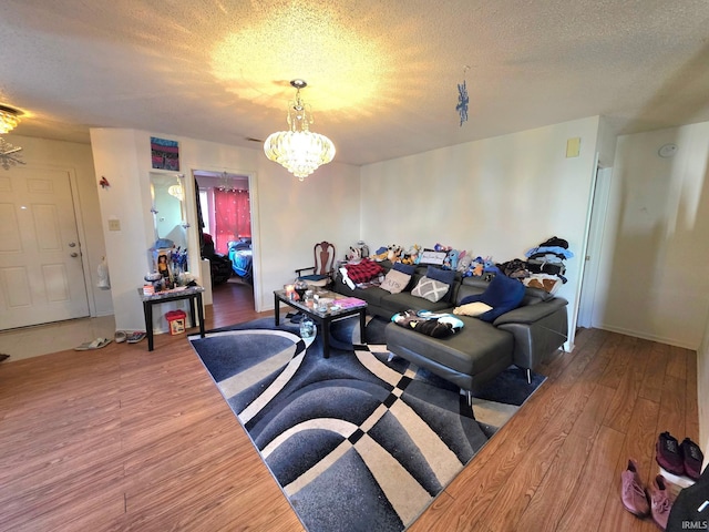 living room with a textured ceiling, a chandelier, wood finished floors, and baseboards